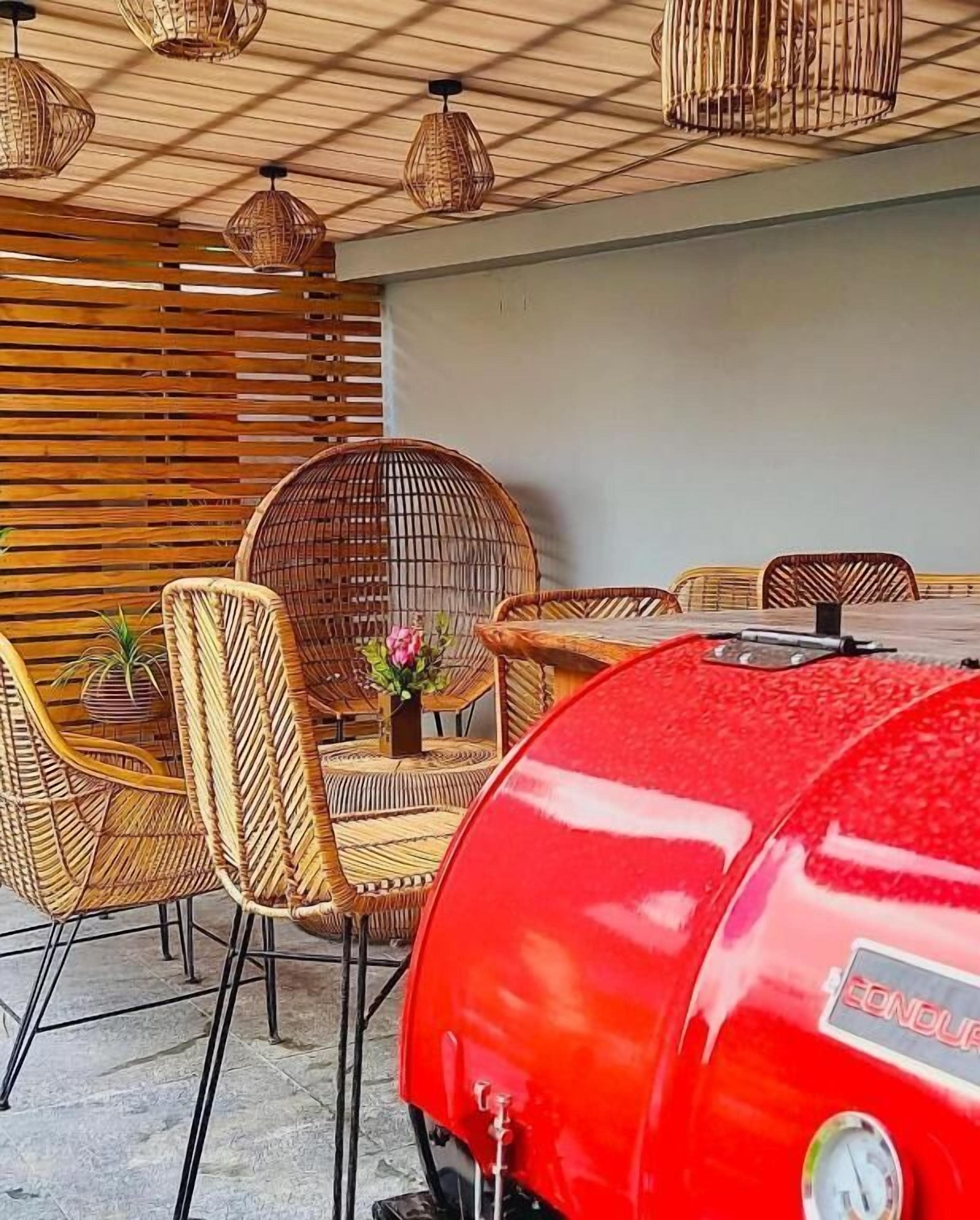 A patio area with wicker furniture, a red grill, and hanging lights.