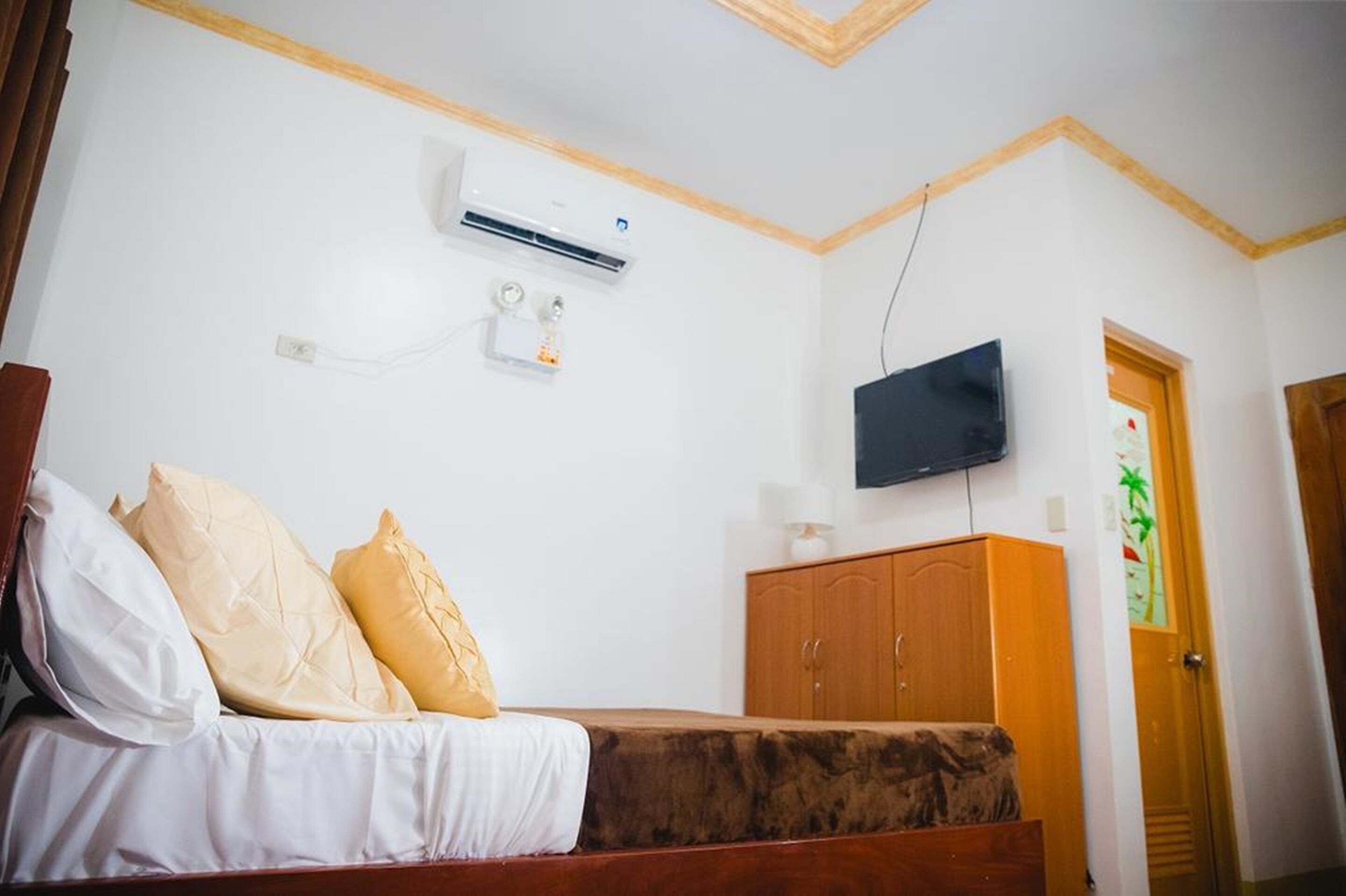 Un dormitorio con cama, aire acondicionado, televisor y armario de madera.