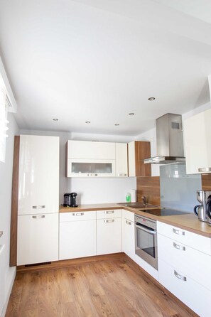 Una cocina moderna con armarios blancos, una campana extractora de acero inoxidable y una encimera de madera.