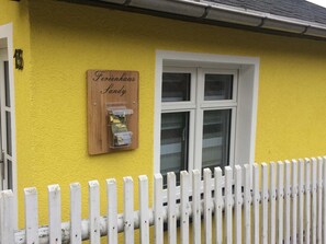 Un edificio amarillo con un letrero de madera que dice "Ferienhaus Sandy" y una ventana.
