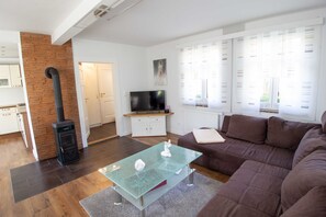 A modern living room with a glass coffee table, a brown sofa, a TV, and a fireplace.