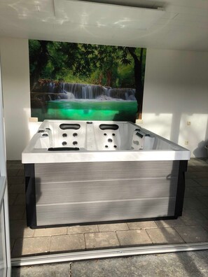 A spa tub with a waterfall mural in the background.