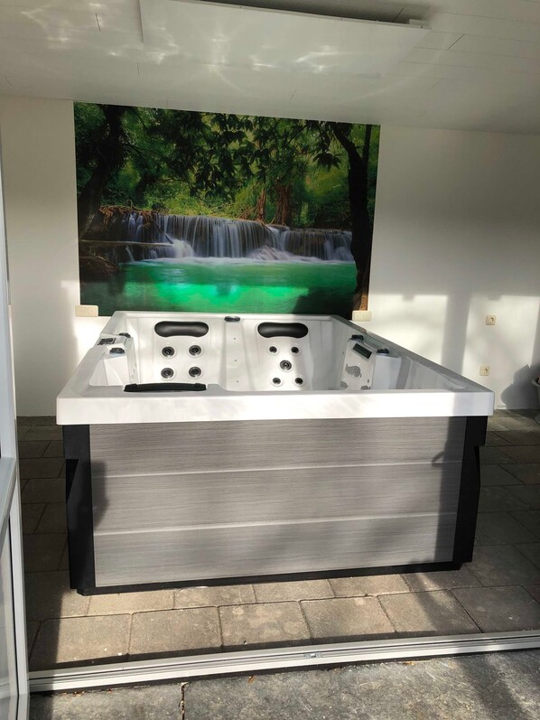 A spa tub with a waterfall mural in the background.