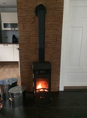 A modern kitchen with a wood-burning stove, a coffee maker, and two metal containers on the counter.