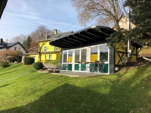 Una casa amarilla con un porche cubierto.