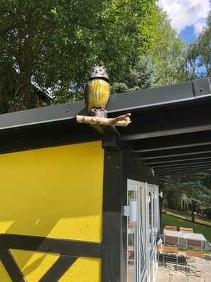Un edificio amarillo con techo negro y una escultura de pájaro en la parte superior.