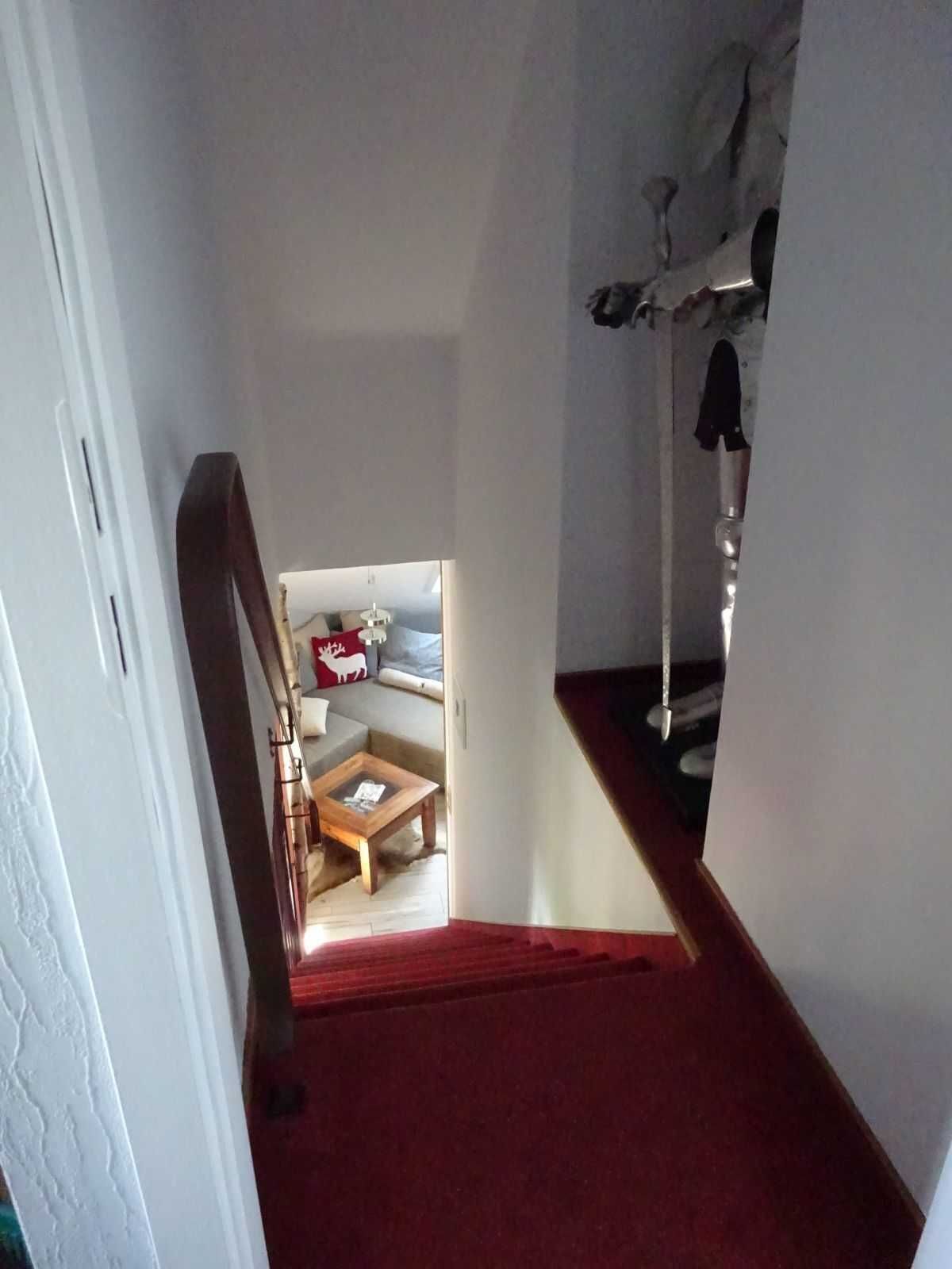 A narrow hallway with a red carpet leading to a living area with a sofa and a coffee table.
