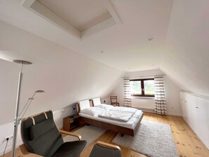 Une chambre avec un puits de lumière, un lit, un bureau et une chaise.