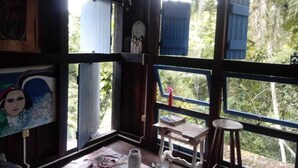 Um quarto com janelas amplas, uma mesa pequena e uma cadeira.