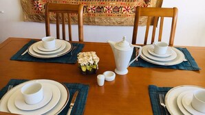 Une table à manger dressée pour six personnes, avec des assiettes, des tasses et un pichet.