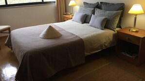 Un lit bien fait, agrémenté d’un coussin décoratif, de deux lampes de chevet et d’une fenêtre avec des rideaux.