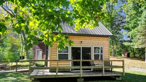A log cabin with a porch, large windows, and a metal roof.