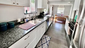 Een moderne keuken met witte kastjes, een granieten aanrechtblad, een roestvrijstalen koelkast en een ingebouwde oven.