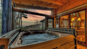 A hot tub in a wooden cabin with a view of trees and a sunset. - Cozy View-  Hot Tub | Screened Porch | Incredible Views (Blue Ridge)
