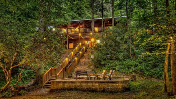 A wooden cabin with a staircase leading to a deck, surrounded by dense forest. - Colby's Cabin- Pet Friendly | Creek Access | Screened Porch (Blue Ridge)