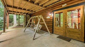 A log cabin with a swing set, stone walls, and a wooden door. - Colby's Cabin- Pet Friendly | Creek Access | Screened Porch (Blue Ridge)