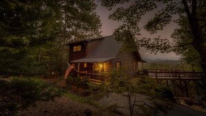 A log cabin with a porch and deck, surrounded by trees and a mountain view. - Heavens Whisper- Lake and Mountain Views | Outdoor Fire Pit | Aska Adventure Area (Blue Ridge)