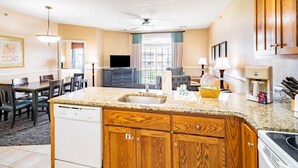 Una cocina moderna con encimeras de granito, armarios de madera y lavavajillas integrado.