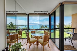 Ein Zimmer mit Glaswand, das auf einen Golfplatz und den Ozean blickt.