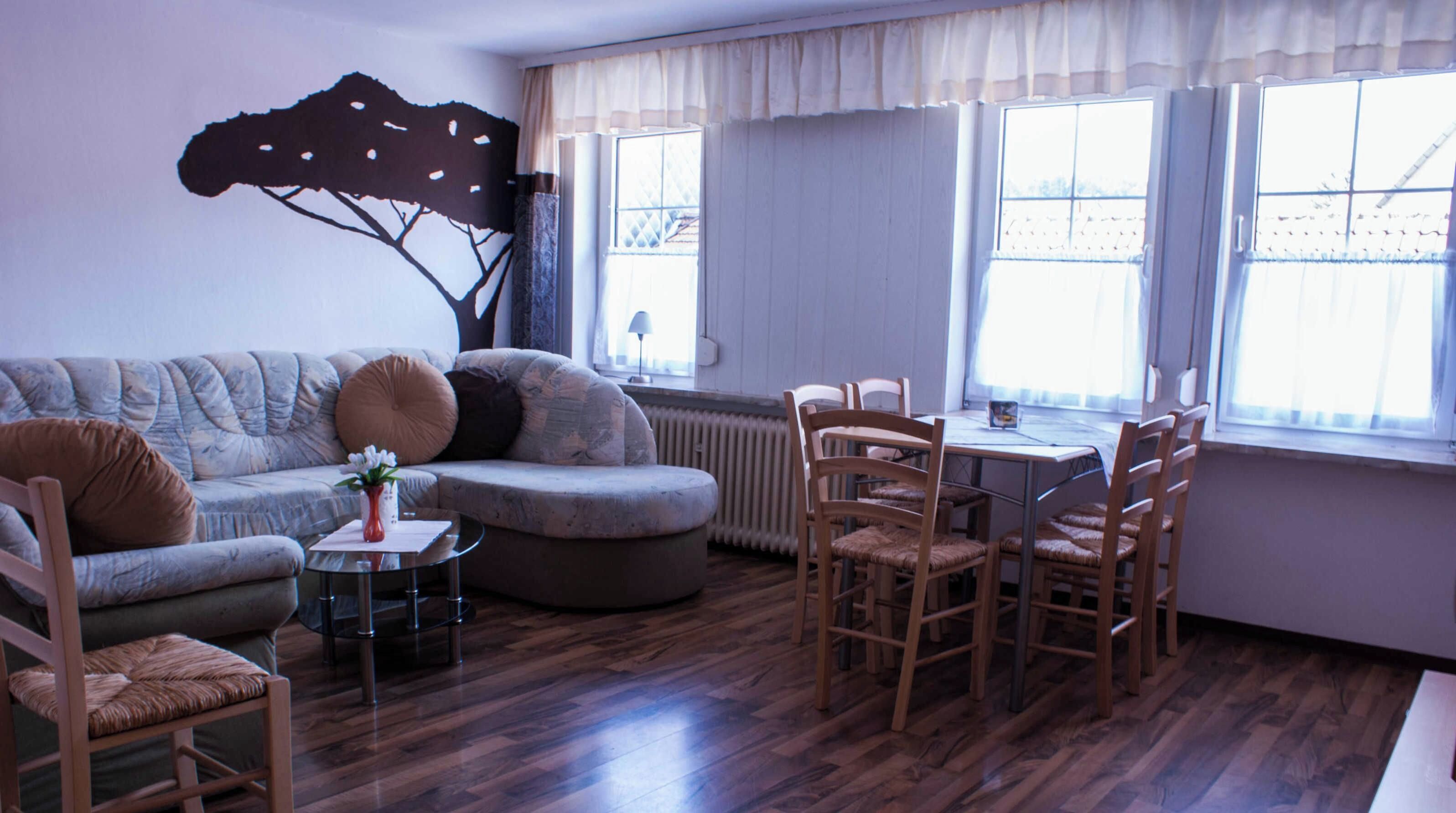 A living room with a sofa, chairs, a coffee table, and a dining table with chairs.
