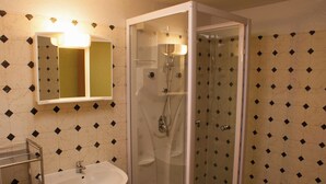 Une salle de bain avec une douche à parois de verre, un lavabo et un miroir avec un éclairage au-dessus.