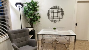 Un espace repas moderne avec une chaise à revêtement gris, une table en verre et des chaises transparentes.