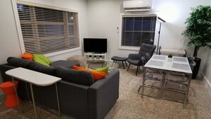 Un salon moderne avec un canapé gris, une petite table et un téléviseur.