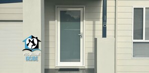 Ein Haus mit einem Schild für Haustiere, einer Tür und einem Fenster mit Jalousien.