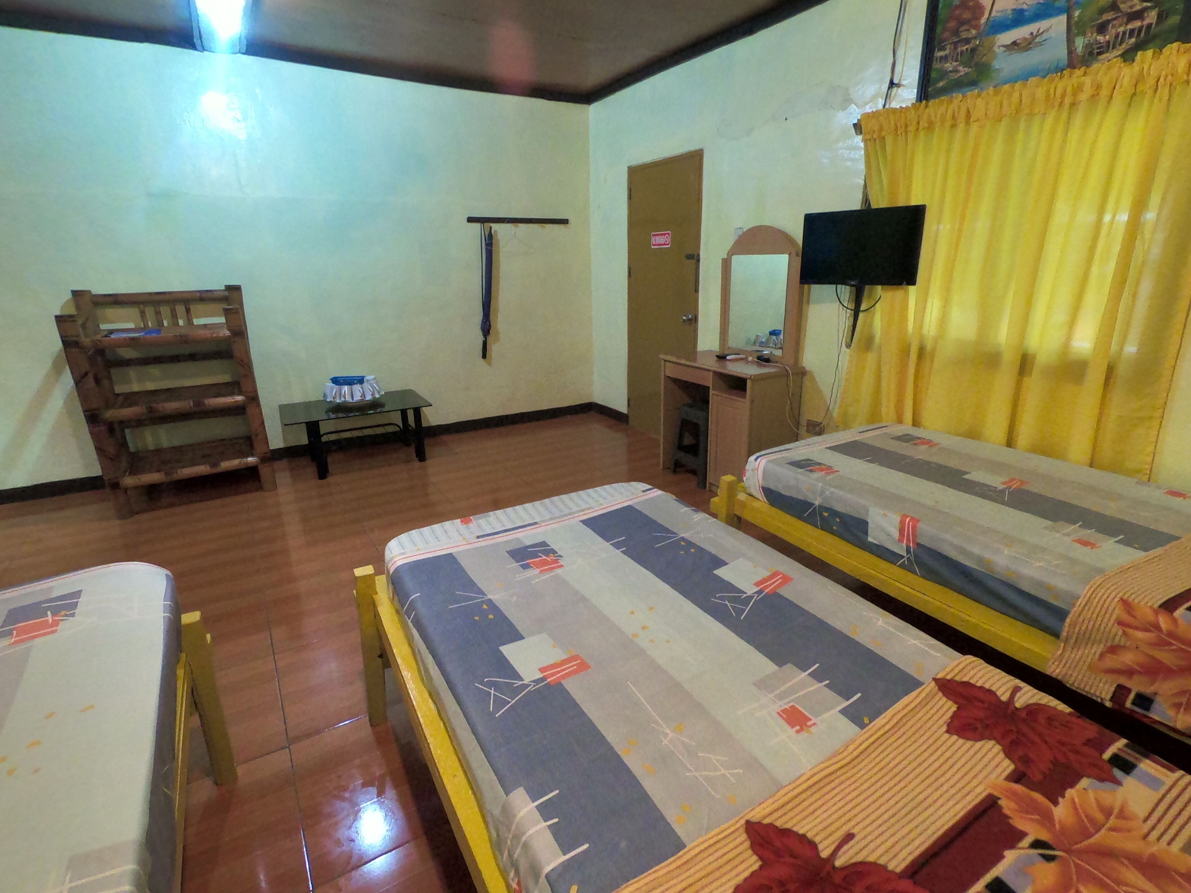 A room with two beds, a desk, a chair, a wooden ladder, a mirror, and a television.