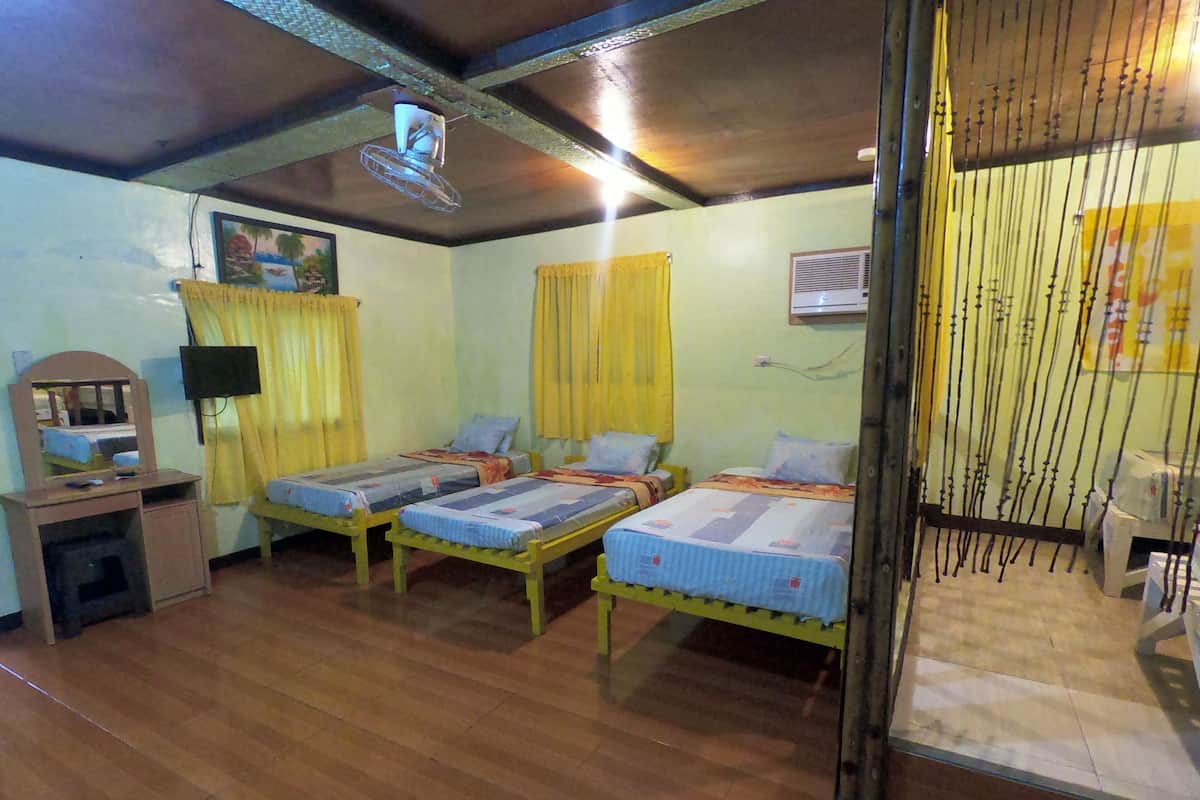 Une chambre avec trois lits en bois, un bureau avec un miroir et un ventilateur de plafond.