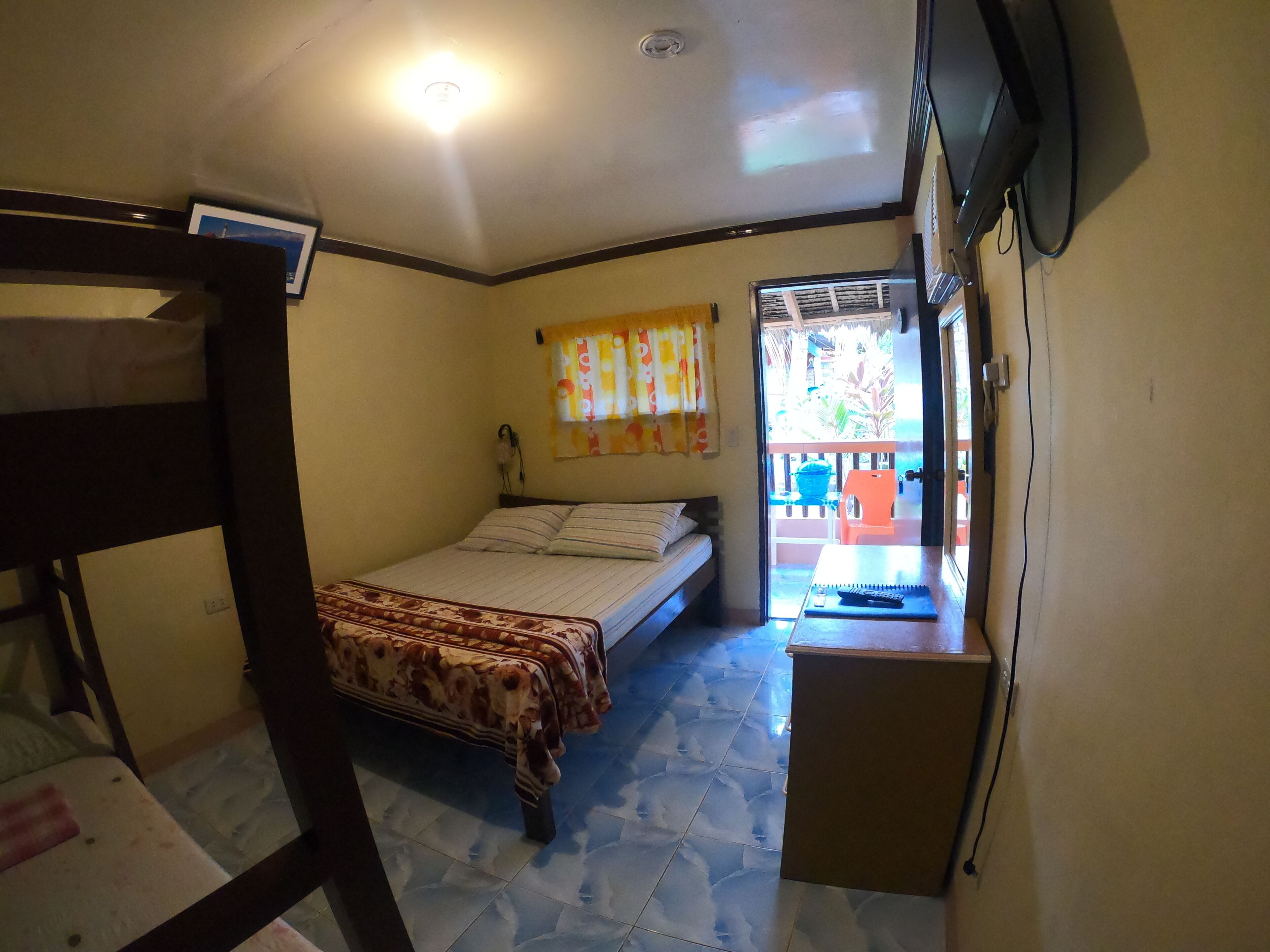 A small, compact room with a bed, a desk, and a television.
