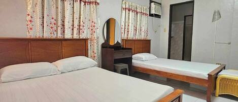 A hotel room with two single beds, a wooden headboard, a small desk with a mirror, and a wardrobe.