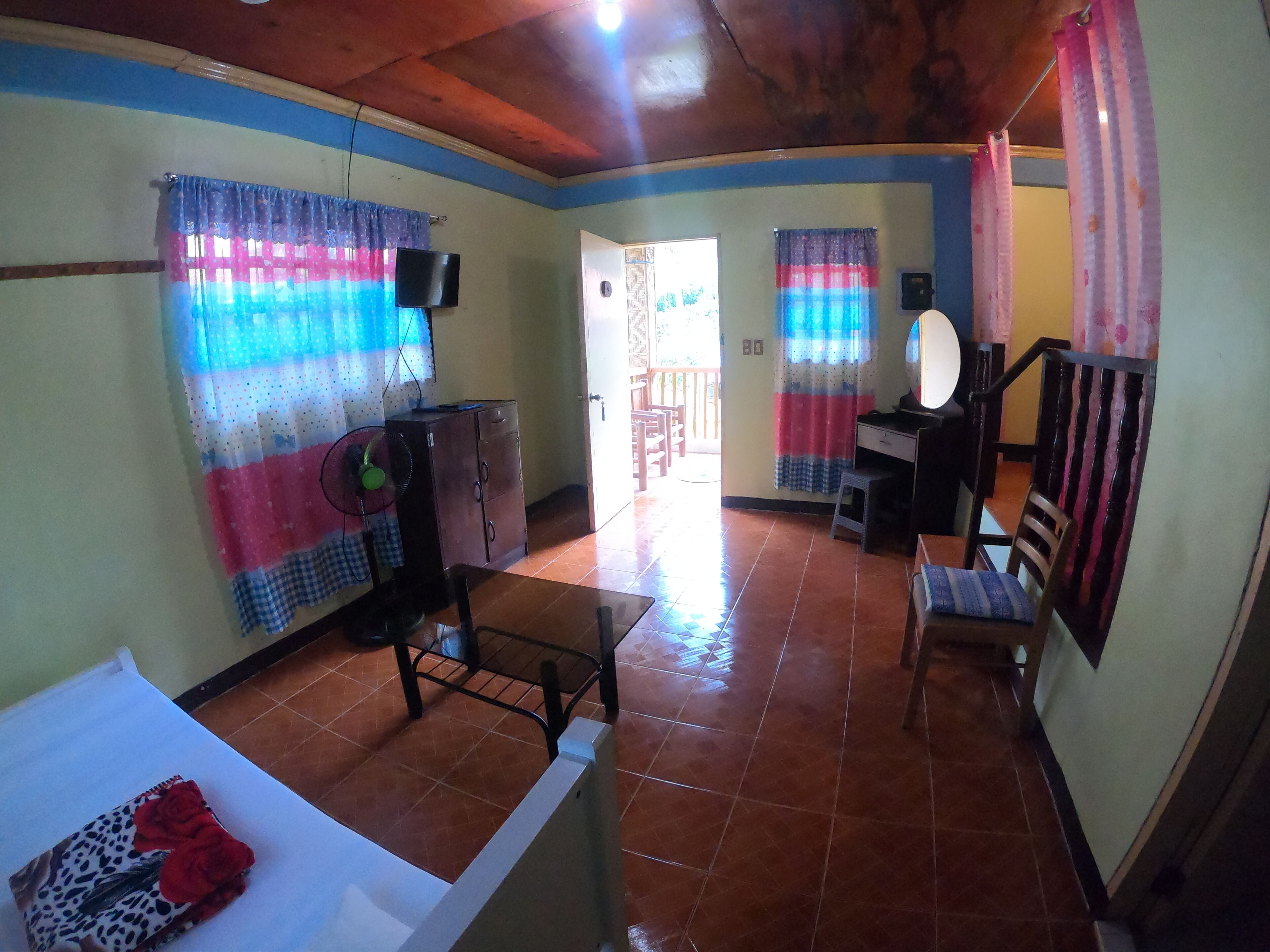 A spacious room with a tiled floor, a wooden ceiling, and a dining area with a table and chairs.