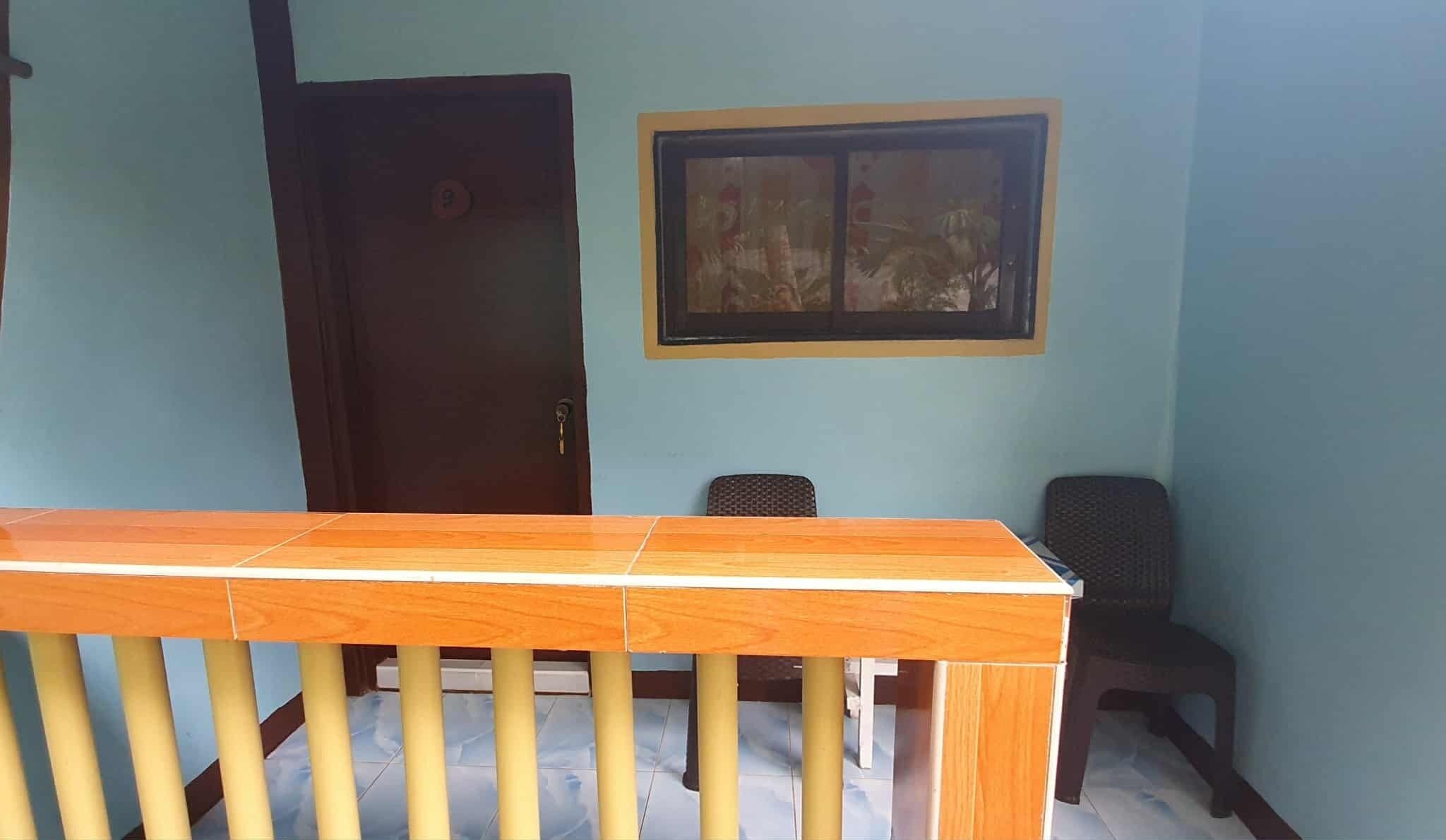 Une pièce avec une table en bois, une porte, une fenêtre et deux chaises.