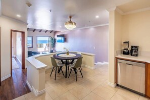 A modern kitchen with a central island, a dining area with a round table, and a view to the outside.