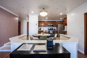 A modern kitchen with wooden cabinets, a central island, and a chandelier.