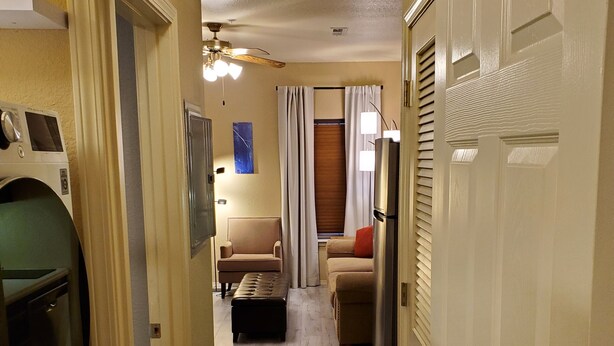 A hallway leading to a living room with a sofa, a coffee table, and a television. There is a washing machine on the left side. - One bedroom resort condo on Golf Course with pool. 10 minutes to SDC! (Branson West)