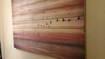 A large wooden wall art with a gradient from light to dark brown, featuring silhouettes of birds.