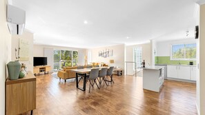 A modern apartment with a dining area, kitchen, and living space. - Luxury Boardwalk Apartment - Unit 7 (NAROOMA)