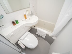 A compact bathroom with a white toilet, a sink with toiletries, and a bathtub. - Super Hotel Yamaguchi Yuda Hot Springs (Yamaguchi)