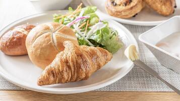 A plate with a croissant, a sandwich, and a salad.