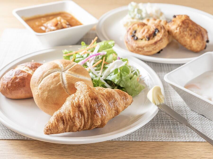 A plate with a croissant, a sandwich, and a salad.