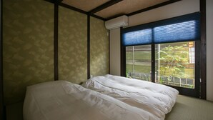 Une chambre à coucher avec un lit, une fenêtre équipée de stores et un appareil de climatisation.