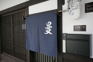 A room with a sliding door, a towel hanging on the door, and a sign with Japanese characters.