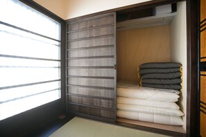 A room with a sliding door closet, a bed with white bedding, and a window with blinds.