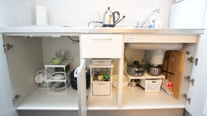 Une cuisine compacte équipée d’un four à micro-ondes encastré, d’une bouilloire et de divers ustensiles et récipients.
