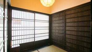 Une pièce de style japonais traditionnel, avec un sol recouvert de tatamis, des paravents shoji et un luminaire suspendu.