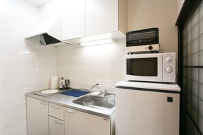 Kitchen area with microwave, refrigerator, sink, and kettle, offering ample space for meal preparation.