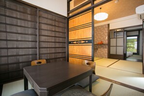 Traditional Japanese-style room with tatami flooring, low table, and cushioned chairs.