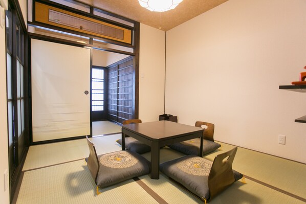 A traditional Japanese room with tatami flooring, a low table, and cushions.